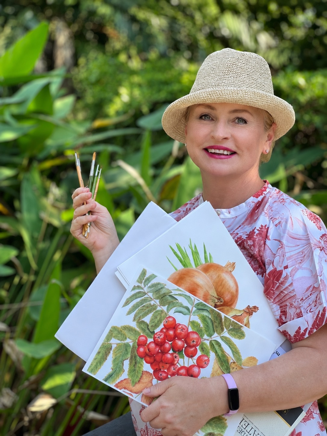 Inessa Falina holding botanical prints and brushes in the garden